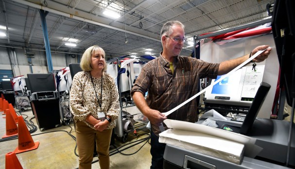 R.F. Shoup of Elections USA, Quakertown, right, examines a voting results report with Anne Norton, Berks County elections operations/systems manager, during voting machine logic and accuracy testing at the county's south campus warehouse in Mohnton on Oct. 3. (BILL UHRICH - READING EAGLE) 10月3日,在位于莫顿的县南部校园仓库进行投票机逻辑和准确性测试时,美国选举协会教克敦的R.F. Shoup(右)与伯克县选举运营/系统经理安妮·诺顿一起检查投票结果报告。(bill uhrich -读鹰)