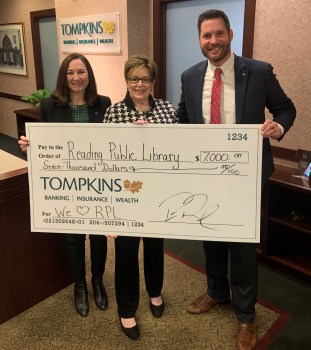 Tompkins Community Bank President Ginger Kunkel, left, and Senior Vice President Peter Rowley, right, present Reading Public Library Director of Advancement and Communications Linda Klein Capozello with a donation to support youth programming at the library's four branches. (Courtesy of Tompkins Community Bank) 汤普金斯社区银行行长姜·昆克尔(左)和高级副行长彼得·罗利(右)向雷丁公共图书馆发展与交流主任琳达·克莱因·卡珀泽罗捐赠,以支持图书馆四个分支机构的青年项目。(汤普金斯社区银行提供)